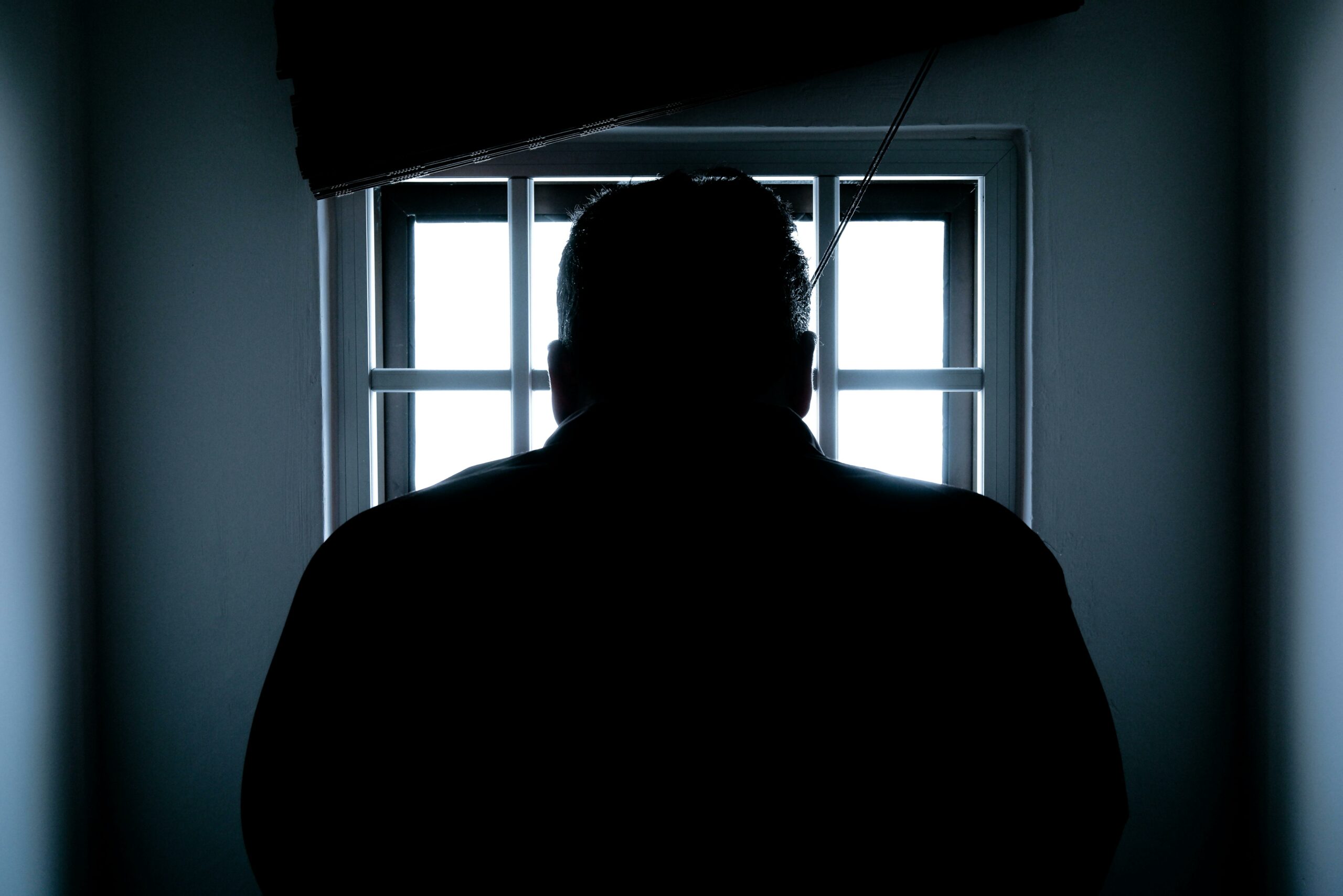 άντρας σε φυλακή κοιτάζει έξω από το μικρό παραθυράκι
