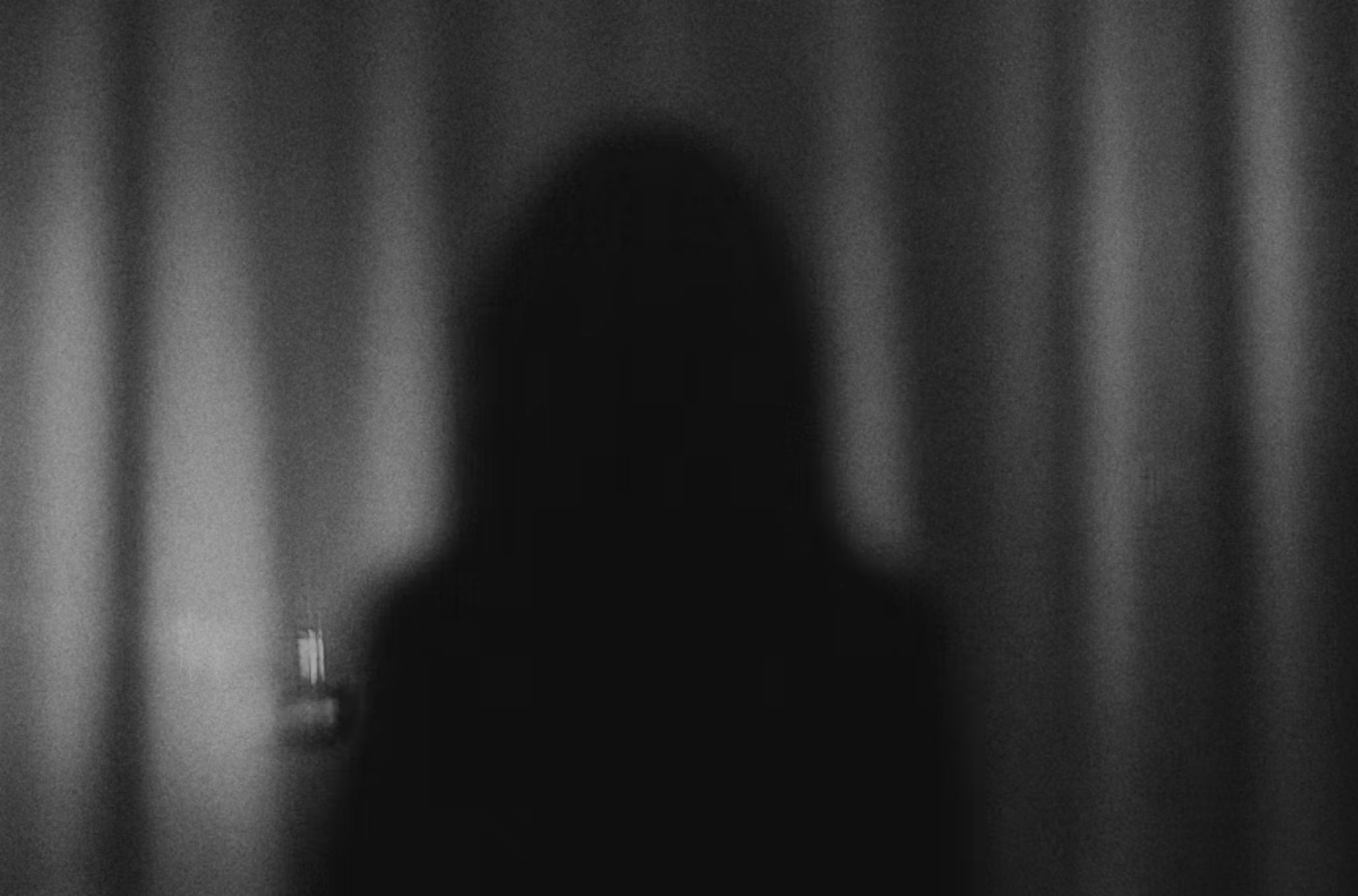 Σκοτεινή εικόνα με άνθρωπο που στέκεται πίσω από κουρτίνα