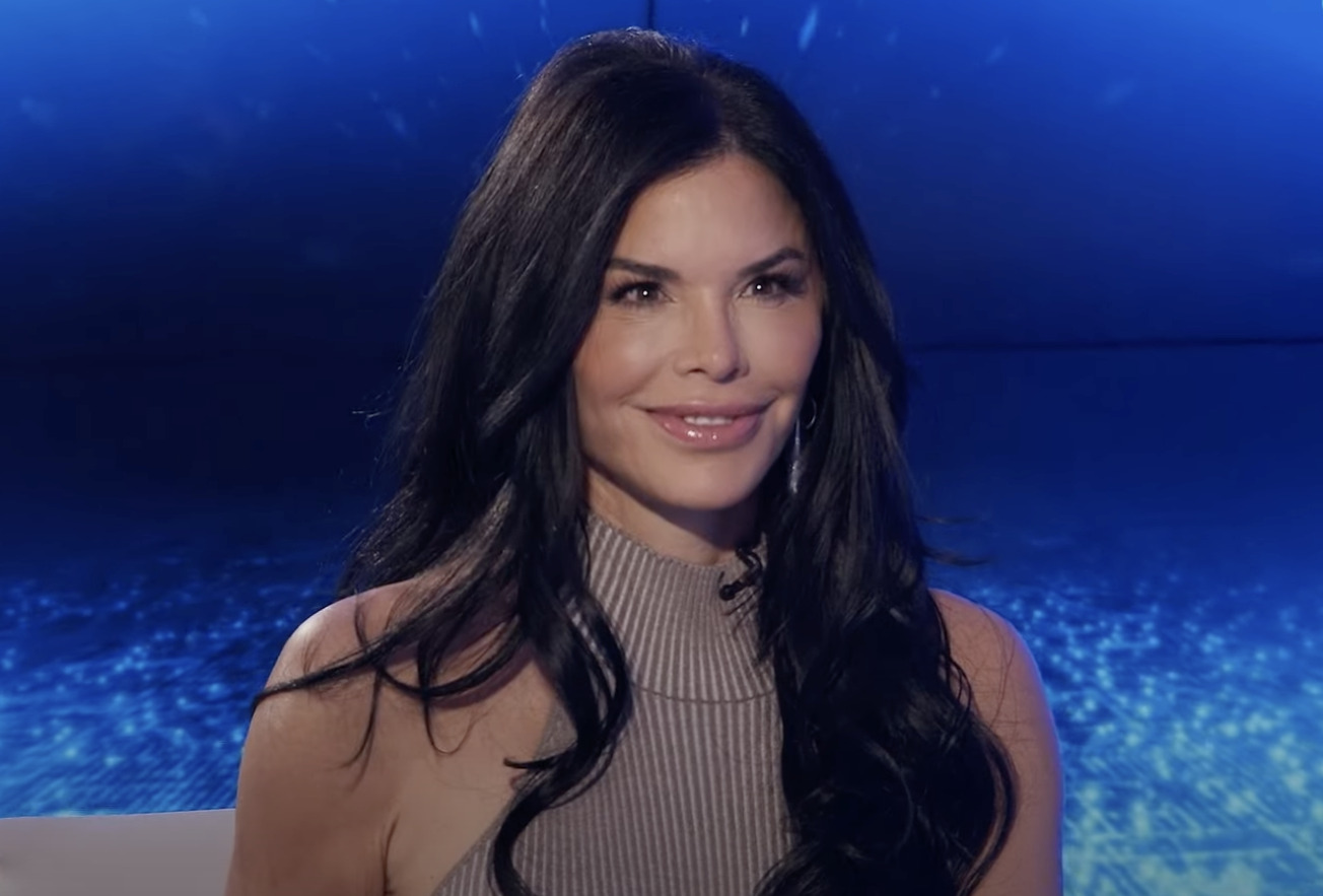 Μελαχρινή γυναίκα που χαμογελάει και έχει πίσω της μπλε φόντο