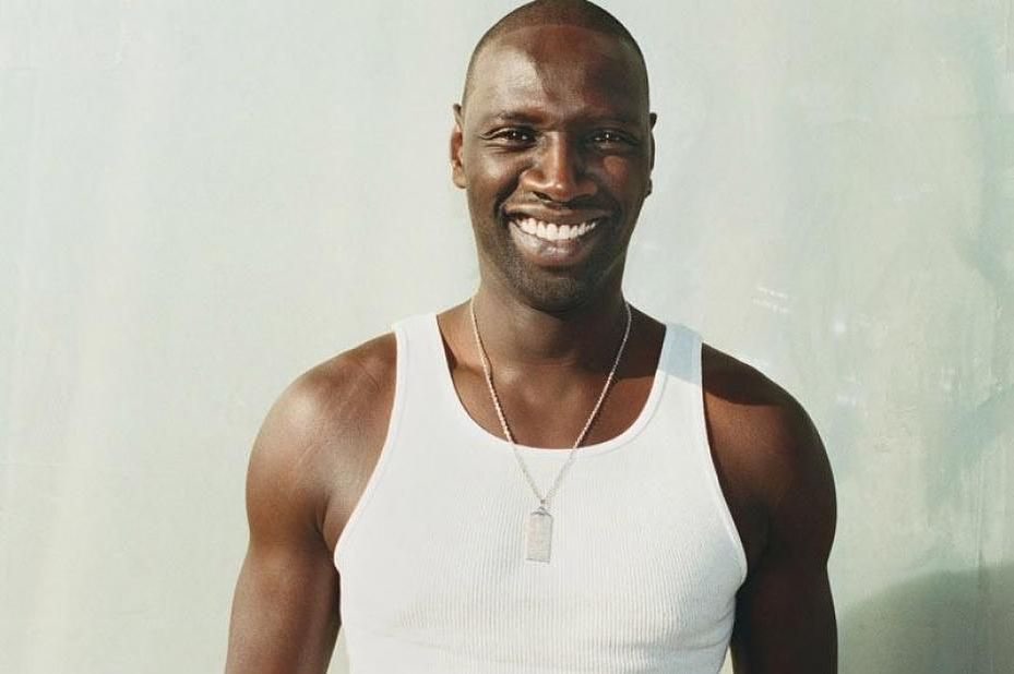 Μελαψός άντρας με λευκό φανελάκι και πλατύ χαμόγελο