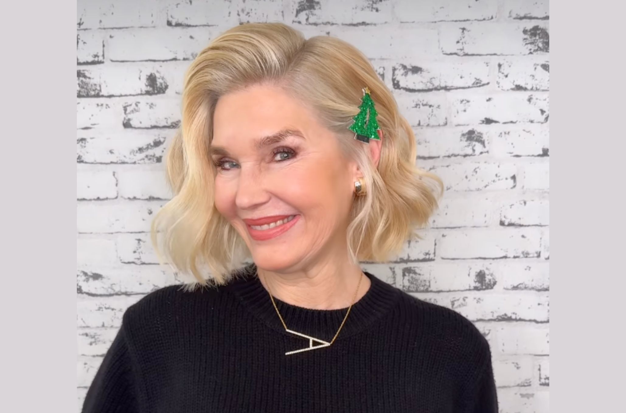 Ξανθιά γυναίκα χαμογελάει και έχει στα μαλλιά της τσιμπίδι με χριστουγεννιάτικο δέντρο