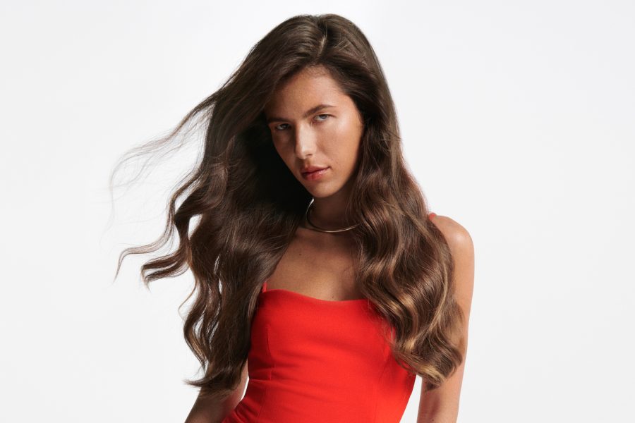 Γυναίκα με πλούσια καστανά μαλλιά και κόκκινη μπλούζα