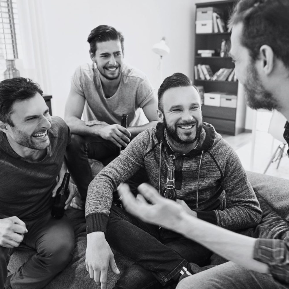 Ασπρόμαυρη εικόνα με τέσσερις άντρες που λένε αστεία και γελάνε