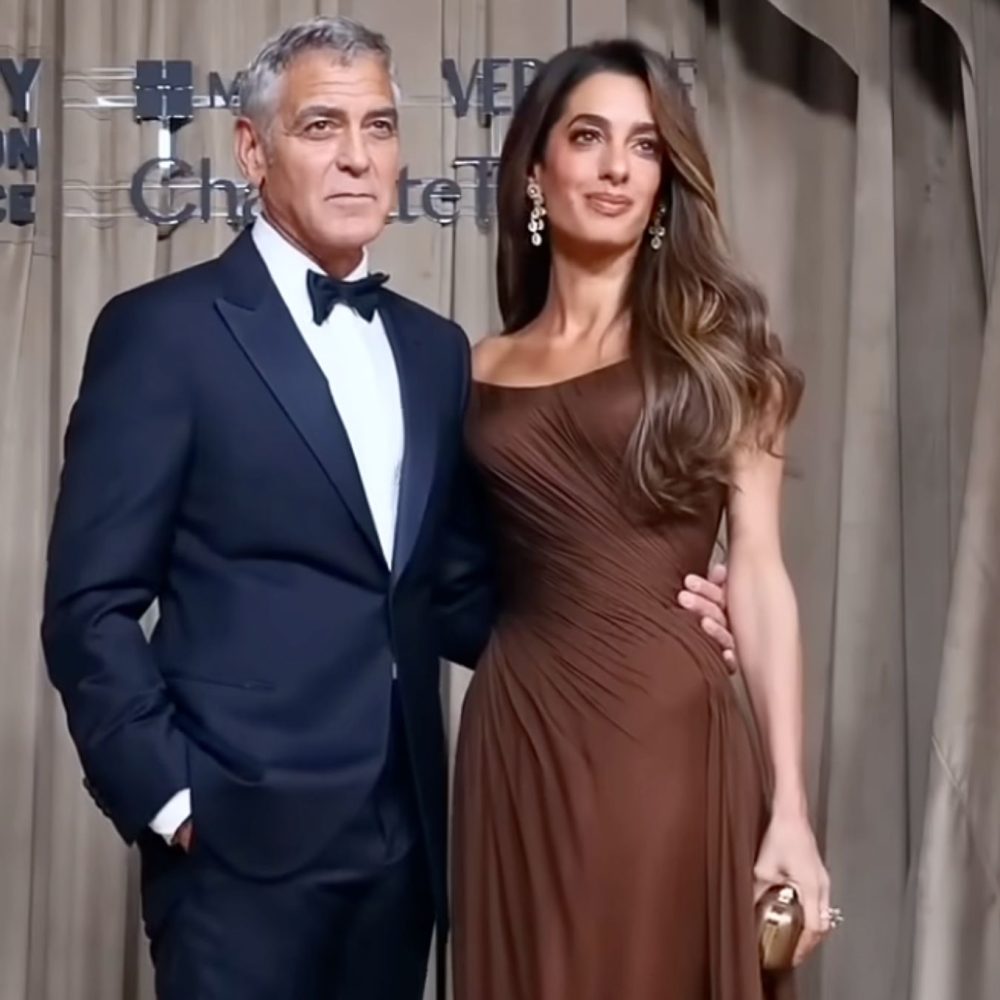 Άντρας με κοστούμι και παπιγιόν κρατάει με το χέρι του γυναίκα με καφέ φόρεμα