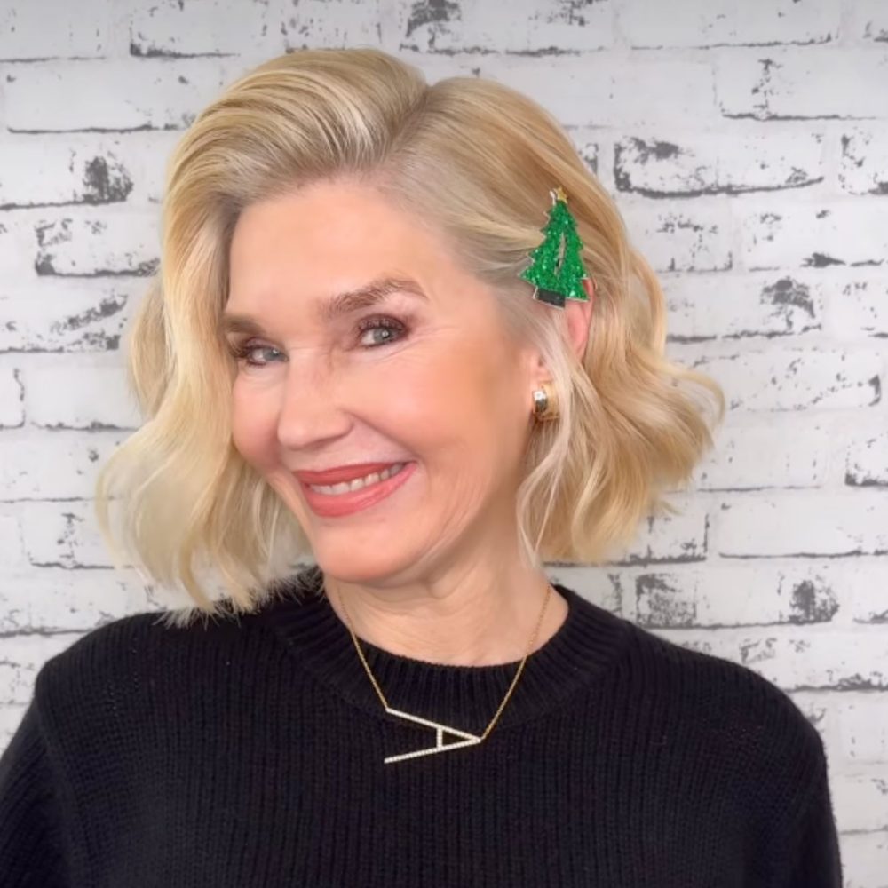 Ξανθιά γυναίκα χαμογελάει και έχει στα μαλλιά της τσιμπίδι με χριστουγεννιάτικο δέντρο