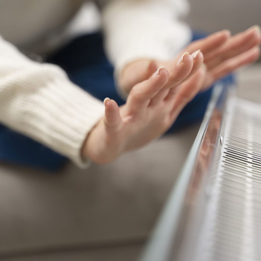 Γυναίκα ζεσταίνει τα χέρια της σε καλοριφέρ