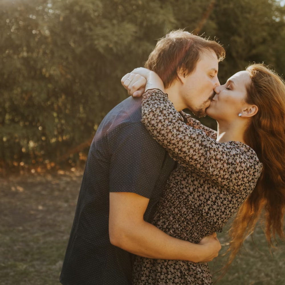 Άντρας και γυναίκα φιλιούνται σε φυσικό τοπίο
