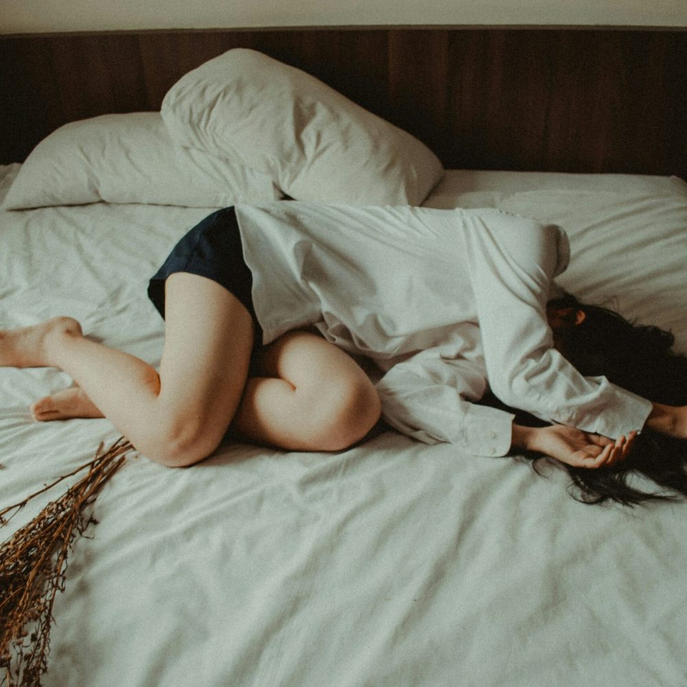 Γυναίκα ξαπλωμένη στο κρεβάτι που μοιάζει να πονάει