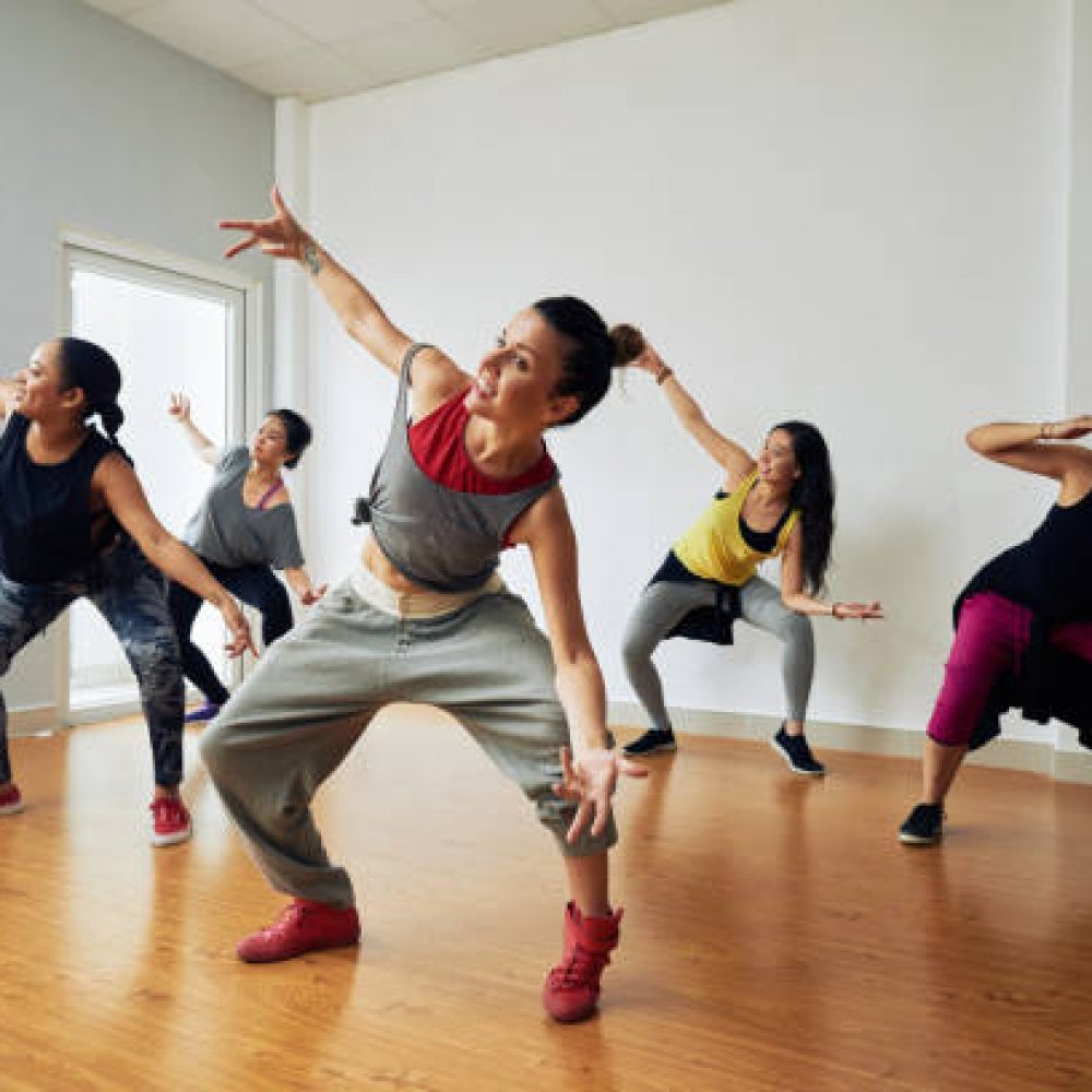 Group of energetic hip-hop dancers focused on training while gathered together in spacious dance hall