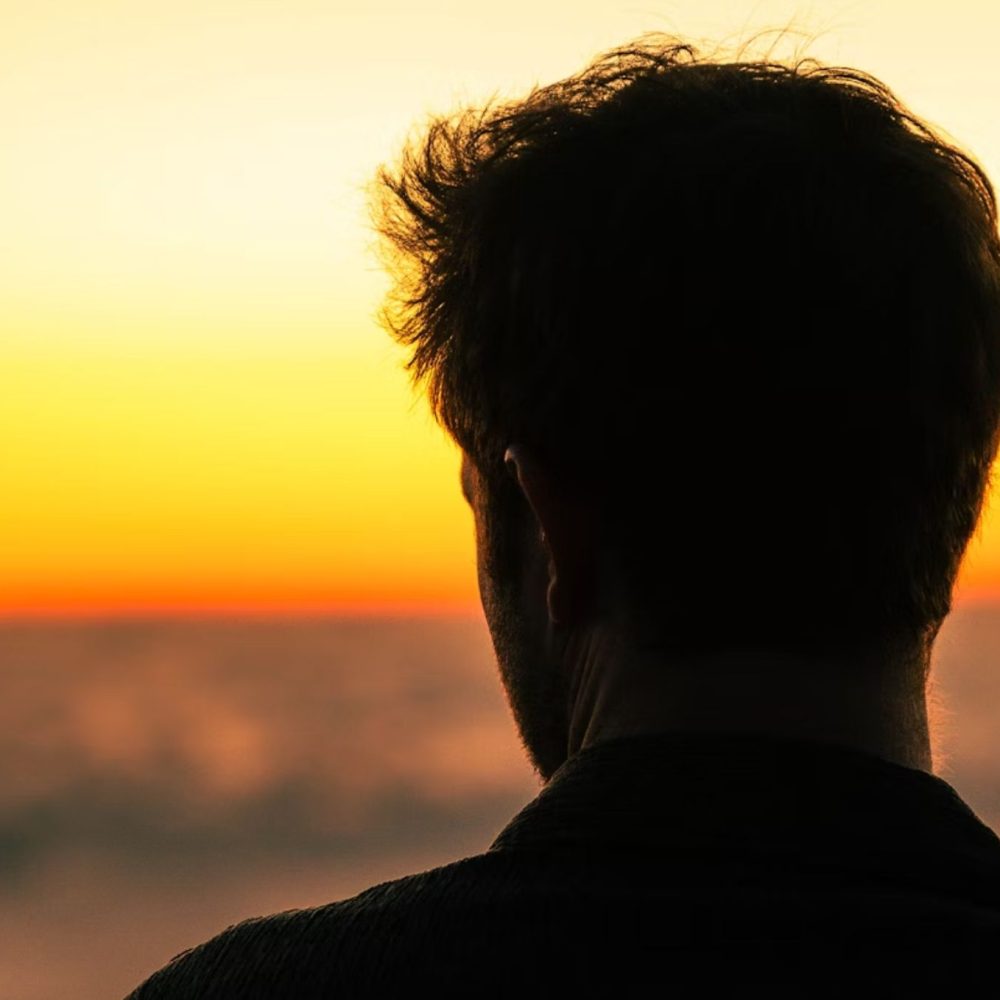 Άντρας με πλάτη κοιτάζει ηλιοβασίλεμα